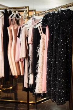 Close-up view of various stylish clothes hanging on hangers in boutique. Clothes Stock Photos