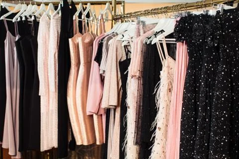 Close-up view of various stylish clothes hanging on hangers in boutique. Clothes Stock Photos