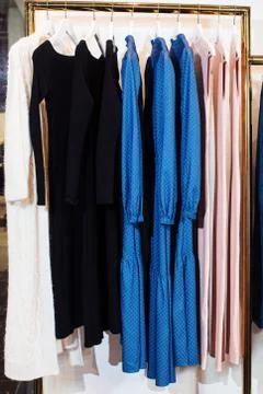 Close-up view of various stylish clothes hanging on hangers in boutique. Clothes Stock Photos
