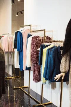 Close-up view of various stylish clothes hanging on hangers in boutique. Clothes Stock Photos
