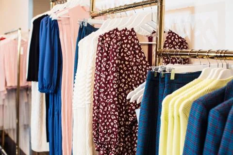 Close-up view of various stylish clothes hanging on hangers in boutique. Clothes Stock Photos