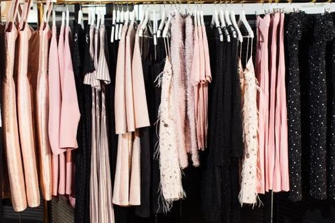 Close-up view of various stylish clothes hanging on hangers in boutique. Clothes Stock Photos