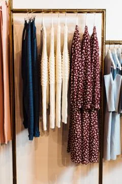 Close-up view of various stylish clothes hanging on hangers in boutique. Clothes Stock Photos