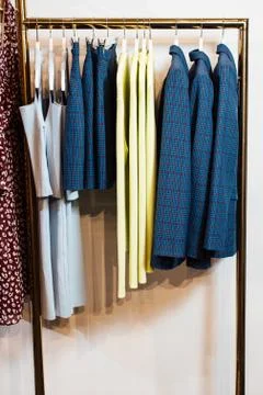 Close-up view of various stylish clothes hanging on hangers in boutique. Clothes Stock Photos