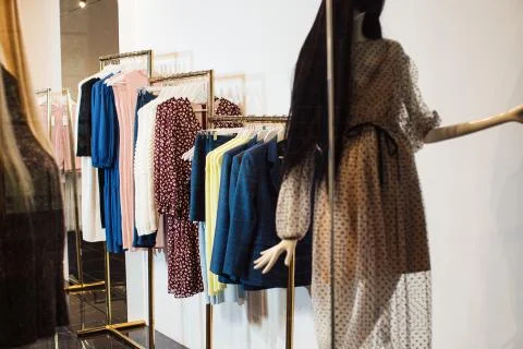 Close-up view of various stylish clothes hanging on hangers in boutique. Clothes Stock Photos