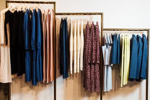 Close-up view of various stylish clothes hanging on hangers in boutique. Clothes Stock Photos