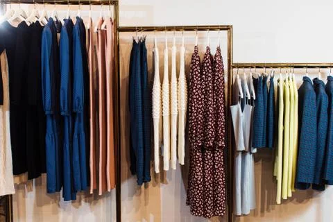 Close-up view of various stylish clothes hanging on hangers in boutique. Clothes Stock Photos