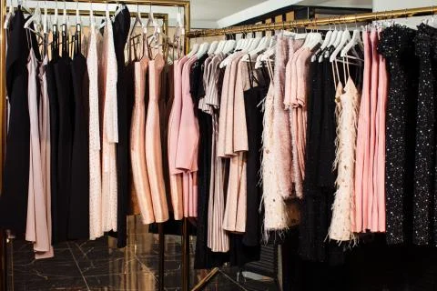 Close-up view of various stylish clothes hanging on hangers in boutique. Clothes Stock Photos