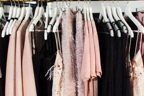 Close-up view of various stylish clothes hanging on hangers in boutique. Clothes Stock Photos