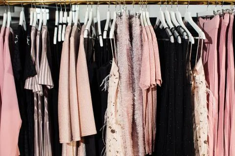 Close-up view of various stylish clothes hanging on hangers in boutique. Clothes Stock-Fotos