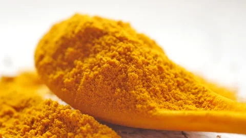 A close-up view of vibrant turmeric powder on wooden spoon and spilled on w.. Vídeos de archivo 333030746