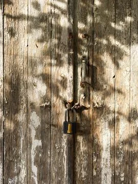 Close up view of a vintage padlock in front of a wooden and mossy barn. iron Stock Photos