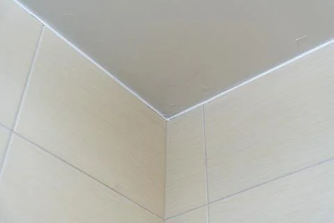 Close-up view of a wall corner featuring a smooth beige tile and subtle paint Stock Photos