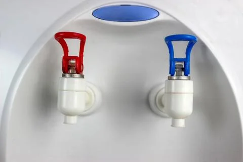 A close-up view of a water dispenser equipped with hot and cold water taps. Stock Photos
