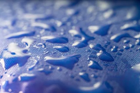 Close-up view on water drops on blue waterproof impregnated textile. Stock Photos