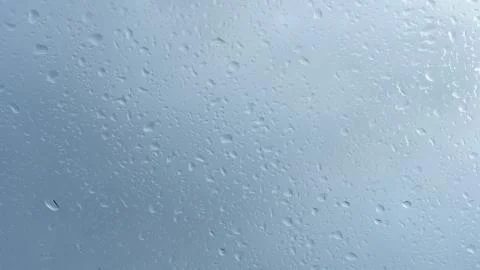 Close up view of water drops falling on glass. Rain running down on window. Stock Photos