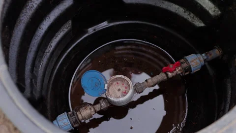Close-up view of water meter and valve in a dark water tank, showcasing gradual Stock Footage 323233644