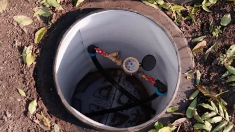 Close-up view of a water meter inside a circular access point, showcasing Stock Footage 323231830