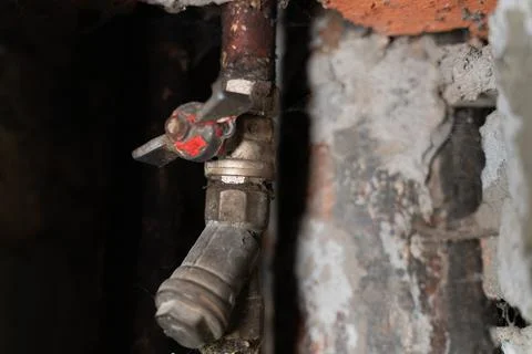 A close-up view of a water meter installed on an old plumbing pipe inside a Stock Photos