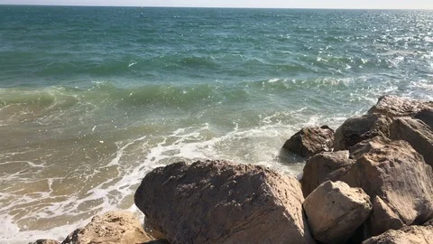 Close up view of waves crashing on rocks summer sun Vilamoura Portugal Stock Footage 98413641