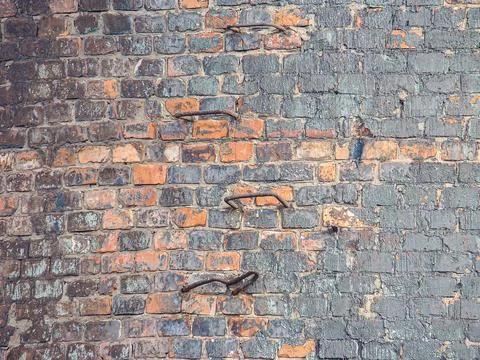 Close-up view of weathered, aged brick wall with vertical red bricks and ho.. Foto stock