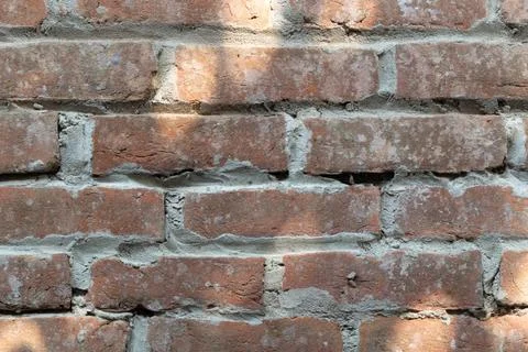 A close-up view of a weathered brick wall with worn red bricks and gray mortar Stock-Fotos