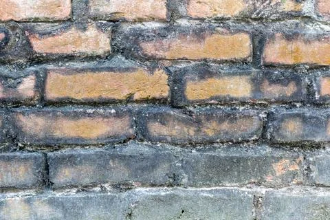 A close-up view of a weathered brick wall with peeling paint and mortar Stock-Fotos