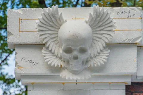 Close-up view of a weathered concrete structure with an aged, winged skull .. Stock Photos