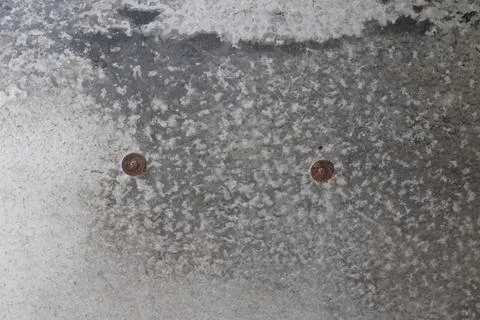 A close-up view of a weathered metal surface with two rusty screws Photos