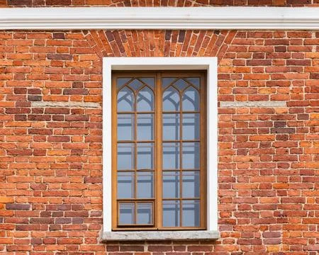 A close-up view of a weathered red brick exterior featuring a wooden-framed.. Stock Photos