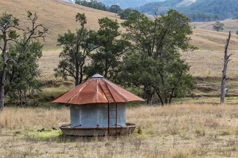 Close-up view of a weathered, rusty cattle feeder standing in a rural paddock Stock Photos