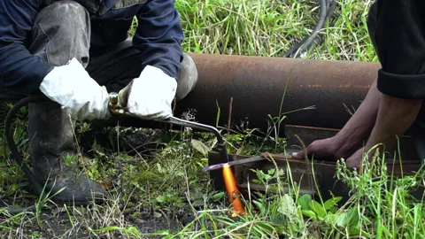 Close up view of a welding machine in the daytime. Workers are cutting off metal Stock Footage 155467185