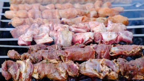 A close view of well-cooked meat on skewers, lying on a steaming brazier. One Stock Footage 91746895