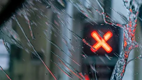 Close-up view of a wet glass surface with raindrops and a red traffic signal Stock Photos