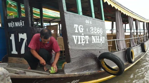 Close-up view where asian man is cutting a coco on the floor of his boat for Stock Footage 67426153