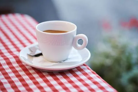 Close-up view of a white ceramic coffee cup on a red and white checkered ta.. Stock Photos