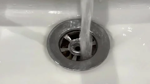 A close-up view of a white ceramic sink. Water is flowing directly into the Stock Footage 326169904