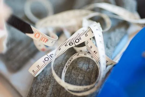 Close up view of white flexible measuring tape coiled over grey knitted fabri Stock Photos