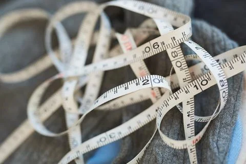 Close up view of white measuring tape tangled on grey wool fabric in fashion  Stock Photos