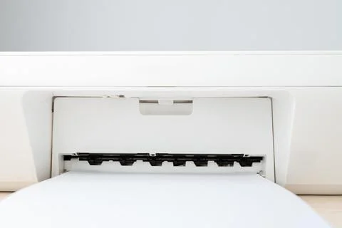Close-up view of a white printer feeding blank paper into the output tray, su Stock Photos
