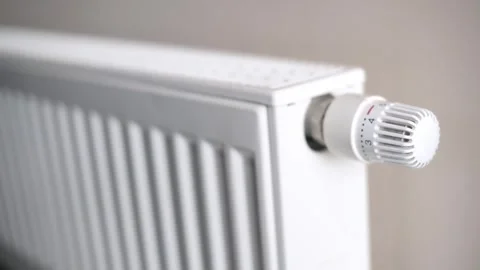 A close-up view of a white radiator with an adjustable thermostat valve. The Stock Footage 283946908