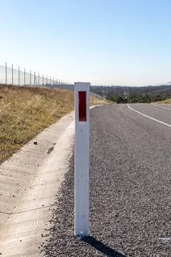 A close-up view of a white roadside guidepost with a red reflector Stock Photos