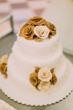 The close-up view of the white wedding cake decorated with chocolade roses. Stock Photos