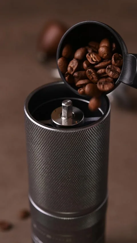 Close-up view of whole coffee beans pouring from a scoop into the open top of a Stock Footage 346743254