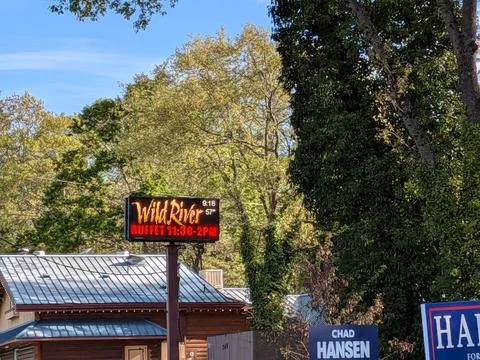 Close view of Wild River Buffet electric sign beside blue-roofed building Fotos de archivo