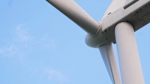 Close-Up View of a Wind Turbine Rotor Blades Spinning Against a Clear Blue Sky Stock Footage 296931042