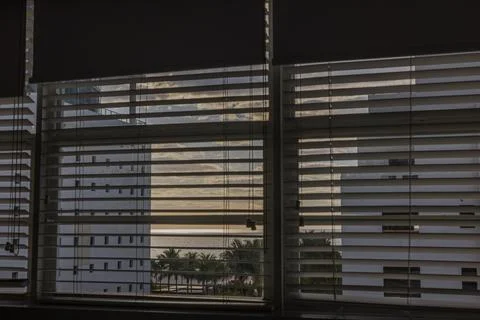 Close-up view of window blinds in hotel room framing sunset over Miami Beach Stock Photos