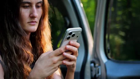 Close-up view of a woman using a smartphone while sitting in a parked... 스톡 동영상 340290948