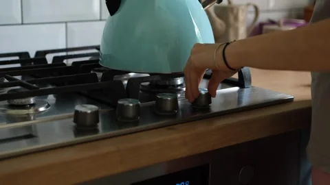 Close-up view of a woman's hand turning on the gas burner to boil water in a Stock Footage 340231814