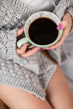 A close-up view of a woman's hands with a cup of morning coffee. 写真素材